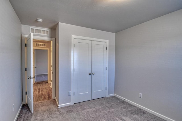 unfurnished bedroom with carpet floors, a closet, visible vents, and baseboards