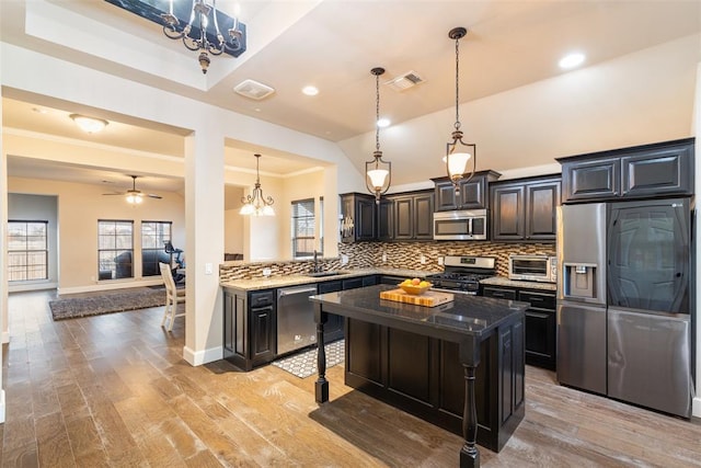 kitchen with a kitchen island, sink, a breakfast bar area, dark stone countertops, and stainless steel appliances