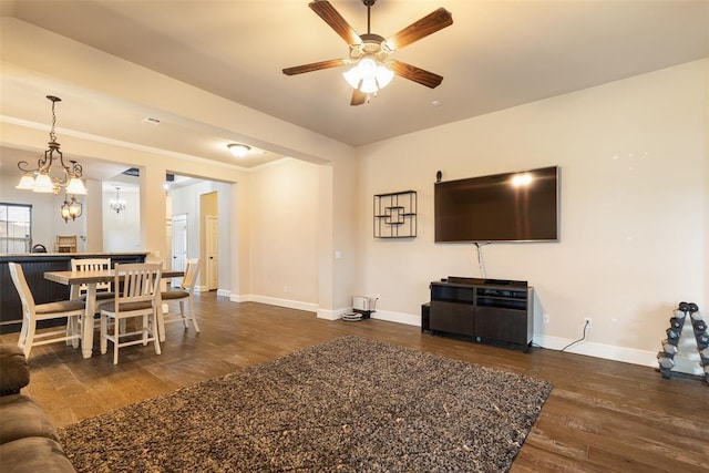 living room featuring dark wood-type flooring and ceiling fan with notable chandelier