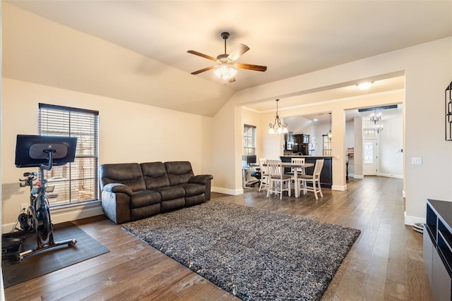 living room with vaulted ceiling, a healthy amount of sunlight, ceiling fan with notable chandelier, and dark hardwood / wood-style floors