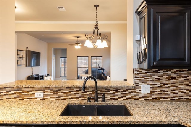 3524 Mount Mitchell Ln, Norman, OK 73069 - kitchen featuring a sink, backsplash, hanging light fixtures, light stone counters, and open floor plan