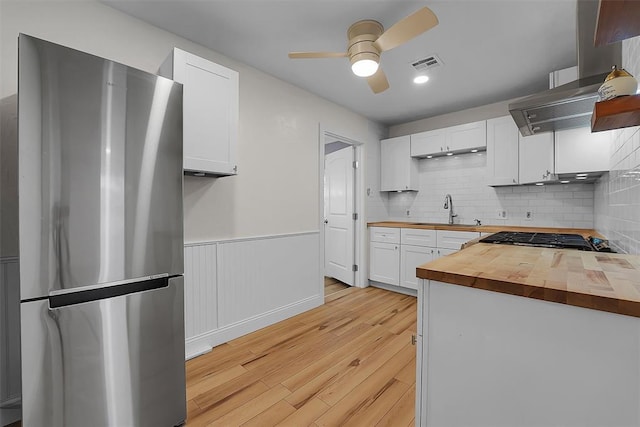 kitchen with sink, gas stovetop, white cabinetry, wooden counters, and stainless steel fridge