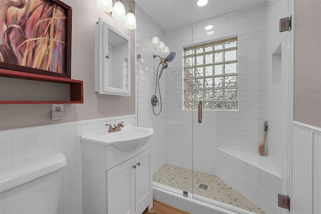 bathroom with toilet, vanity, and a shower with shower door