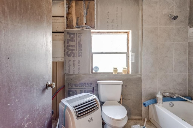 bathroom featuring tile walls, a bathtub, and toilet