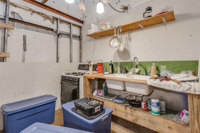 kitchen with white gas range, sink, and decorative light fixtures