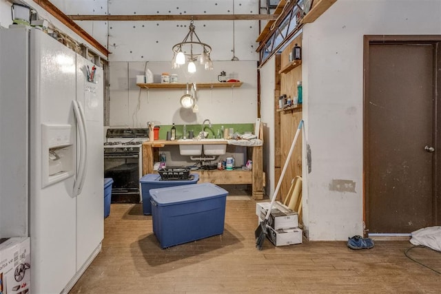 kitchen with sink, hardwood / wood-style flooring, white fridge with ice dispenser, pendant lighting, and gas range oven