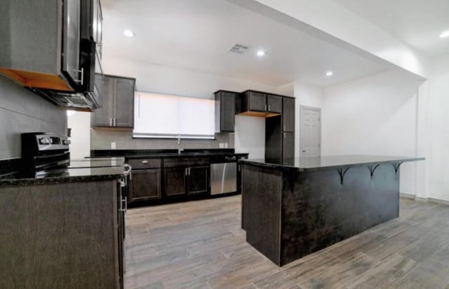 kitchen featuring a kitchen bar, sink, a center island, light wood-type flooring, and stainless steel dishwasher