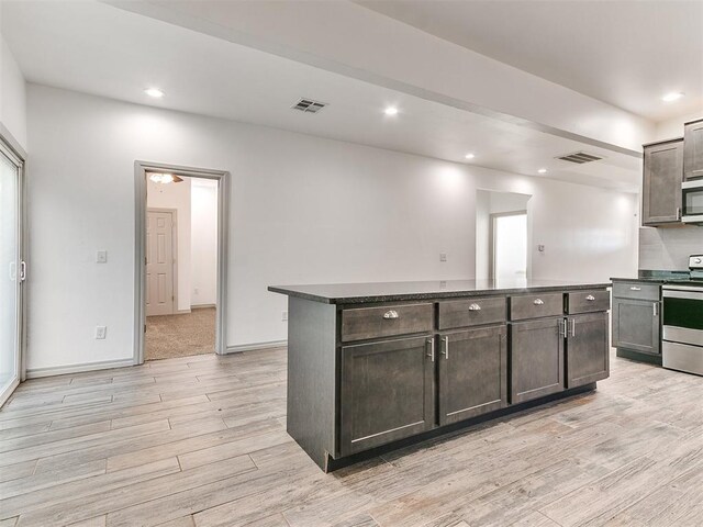 kitchen featuring appliances with stainless steel finishes, dark countertops, visible vents, and light wood-style floors