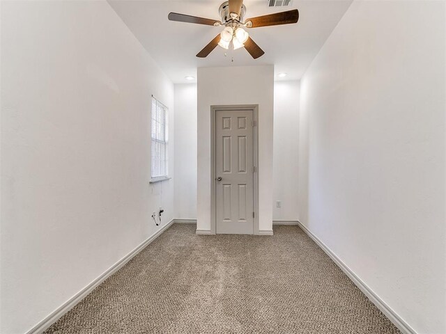 empty room featuring baseboards, a ceiling fan, visible vents, and light colored carpet