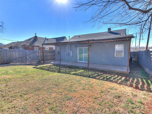 rear view of property with a fenced backyard, a yard, and a chimney
