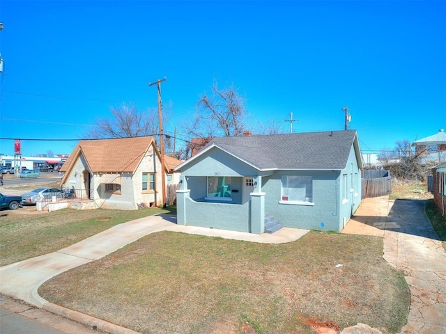 bungalow-style home with concrete driveway, a front yard, and fence