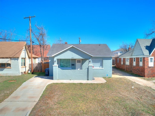 bungalow with driveway, a front lawn, a shingled roof, and fence