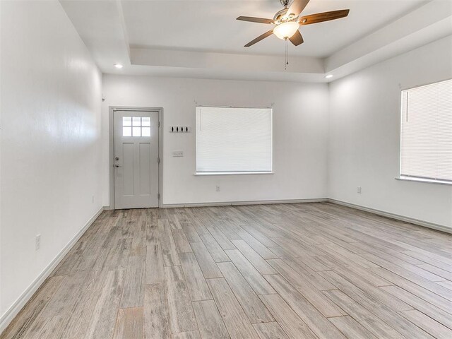 entryway with baseboards, a raised ceiling, ceiling fan, light wood-style flooring, and recessed lighting