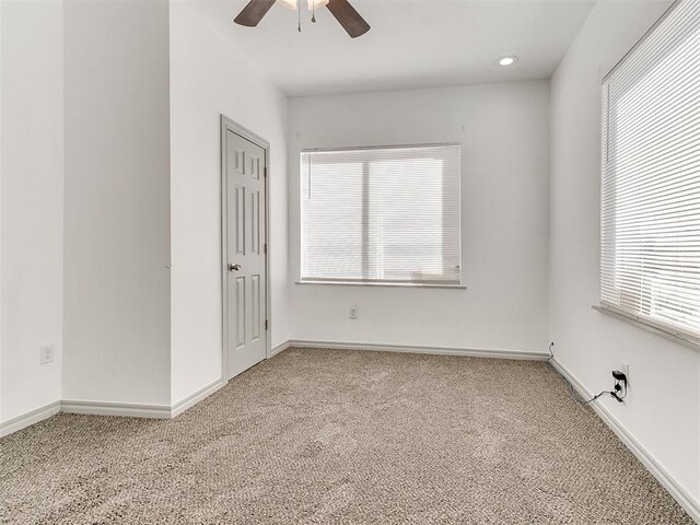 carpeted empty room featuring a ceiling fan and baseboards