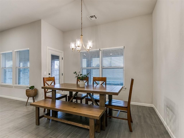 dining space with dark hardwood / wood-style floors and a chandelier