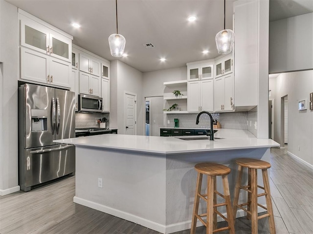 kitchen featuring white cabinetry, sink, hanging light fixtures, and appliances with stainless steel finishes