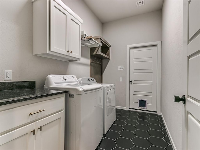 washroom with washing machine and dryer, cabinets, and dark tile patterned floors