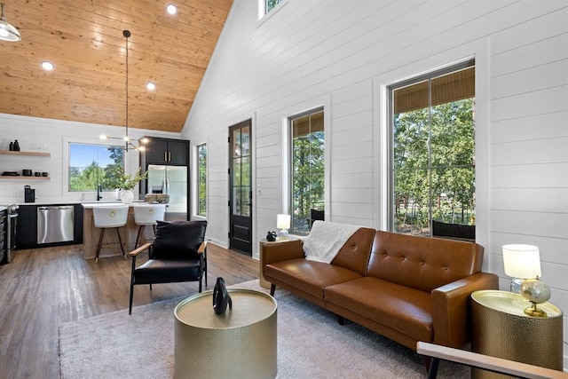 living room featuring plenty of natural light, sink, high vaulted ceiling, and light wood-type flooring