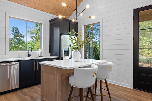 kitchen featuring sink, a center island, vaulted ceiling, light wood-type flooring, and stainless steel appliances