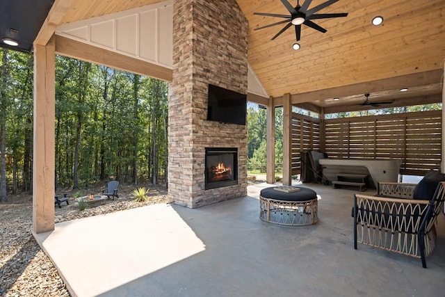 view of patio with ceiling fan, a gazebo, and an outdoor stone fireplace