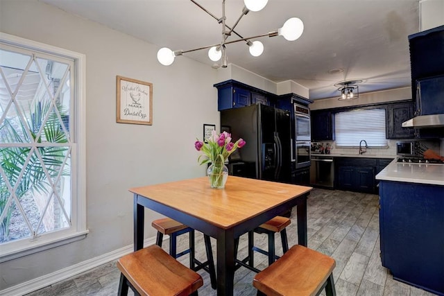 dining area with a chandelier, sink, and light hardwood / wood-style flooring