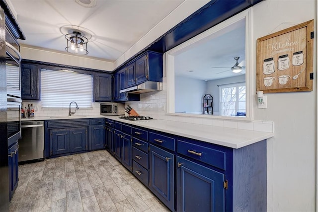 kitchen featuring sink, stainless steel dishwasher, and blue cabinetry