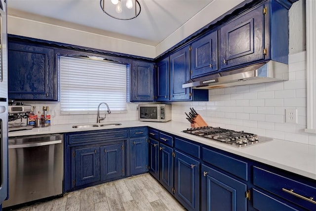 kitchen with sink, blue cabinetry, stainless steel appliances, decorative backsplash, and light wood-type flooring