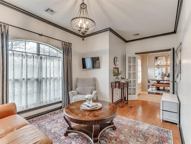 living room with a notable chandelier, ornamental molding, light hardwood / wood-style floors, and a baseboard heating unit