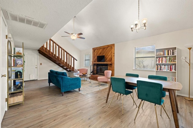 dining room with hardwood / wood-style floors, a textured ceiling, a large fireplace, and a healthy amount of sunlight