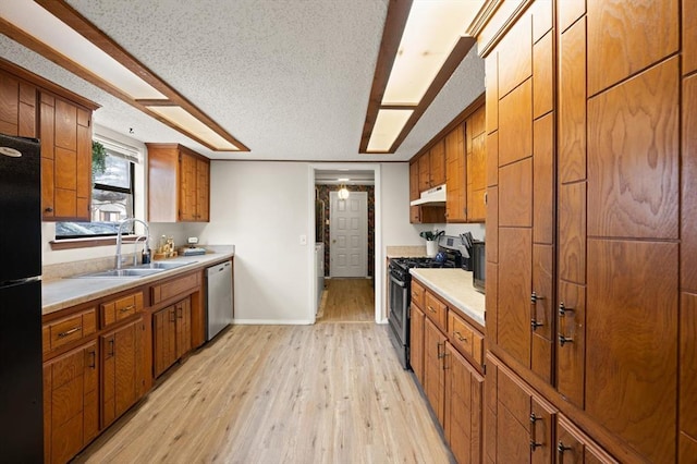 kitchen featuring stainless steel appliances, sink, a textured ceiling, and light wood-type flooring