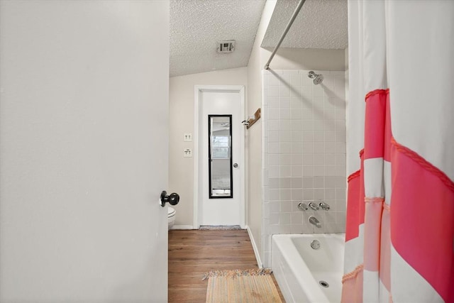 bathroom featuring hardwood / wood-style floors, shower / bath combination with curtain, a textured ceiling, and toilet