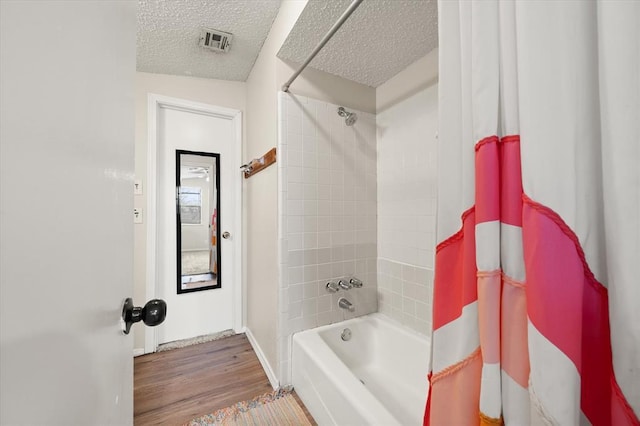 bathroom with wood-type flooring, a textured ceiling, and shower / bath combo with shower curtain