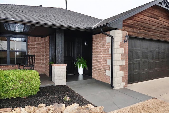 property entrance featuring an attached garage, brick siding, and a shingled roof