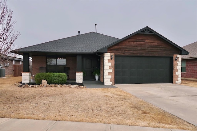 view of front of property featuring brick siding, a shingled roof, central air condition unit, concrete driveway, and an attached garage