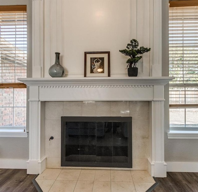 room details featuring baseboards, wood finished floors, and a tile fireplace