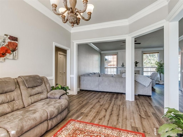 living area with light wood finished floors, a fireplace, crown molding, and an inviting chandelier