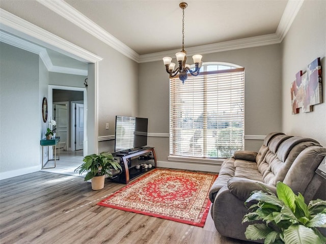 living room featuring ornamental molding, baseboards, an inviting chandelier, and wood finished floors