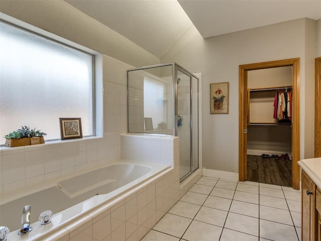 bathroom with a spacious closet, vanity, a shower stall, tile patterned flooring, and a bath