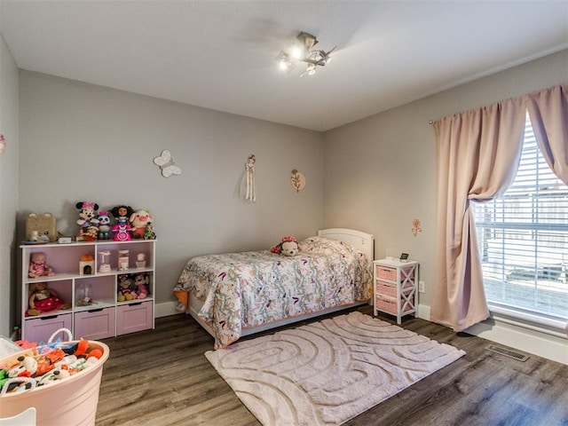 bedroom with wood finished floors, visible vents, and baseboards