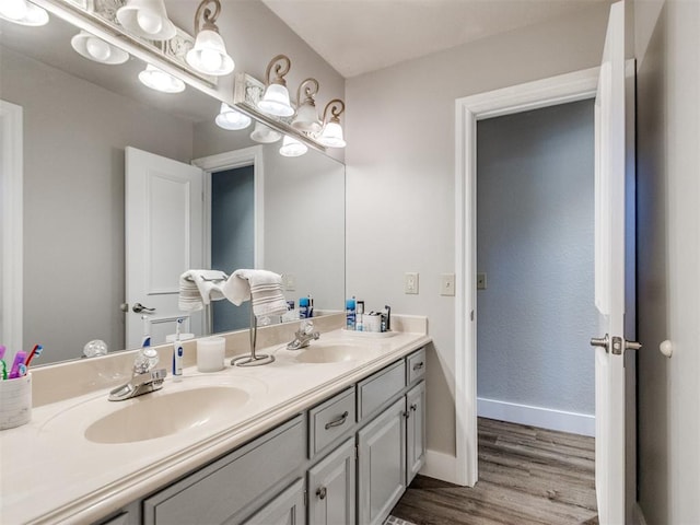 bathroom featuring double vanity, a sink, baseboards, and wood finished floors