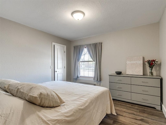 bedroom with dark wood-style flooring and a textured ceiling