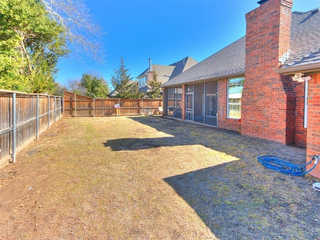 view of yard featuring a sunroom and a fenced backyard