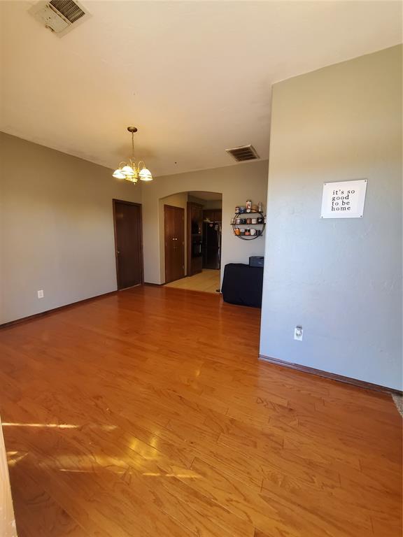 spare room featuring wood-type flooring and a chandelier