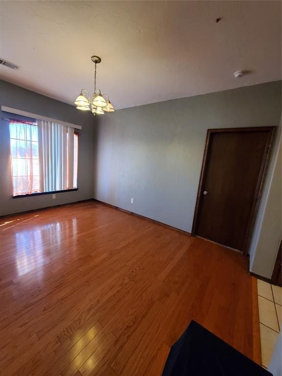 spare room featuring hardwood / wood-style flooring and a notable chandelier