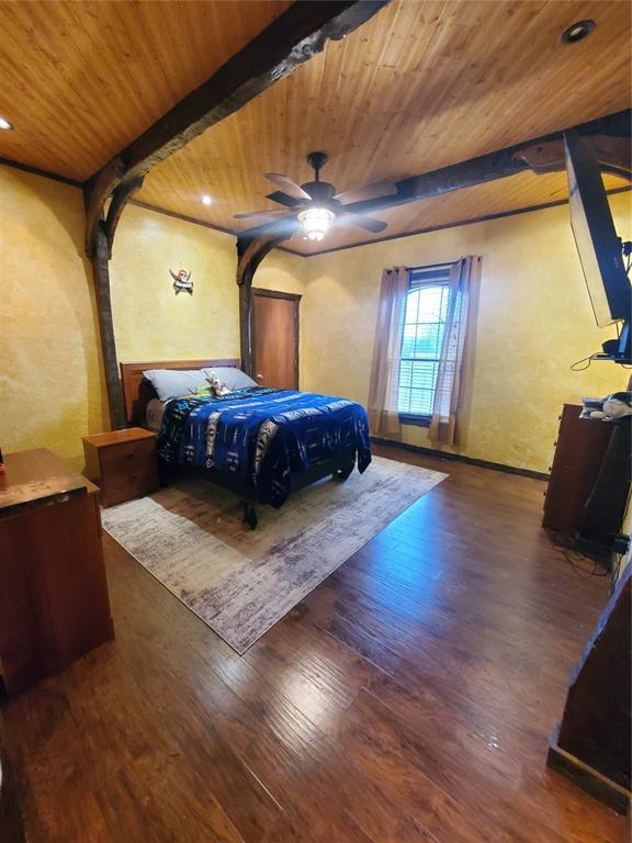 bedroom with beam ceiling, dark wood-type flooring, and wood ceiling