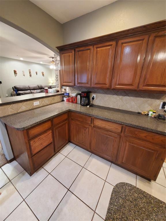 kitchen with backsplash, kitchen peninsula, ceiling fan, and light tile patterned flooring