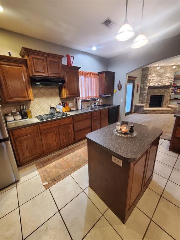 kitchen featuring light tile patterned flooring, pendant lighting, tasteful backsplash, sink, and stainless steel appliances