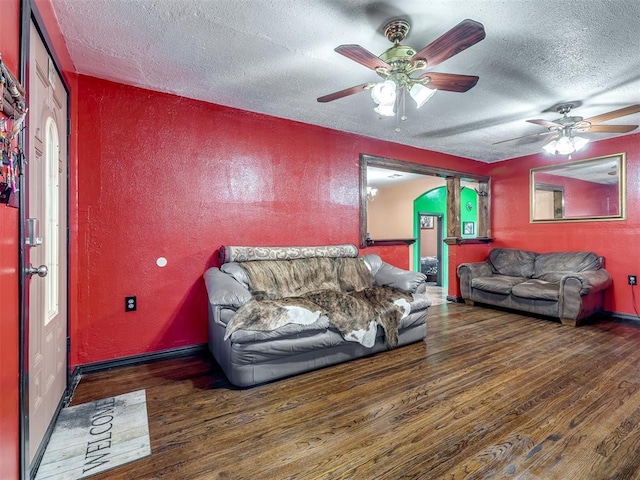 living room with ceiling fan, dark hardwood / wood-style floors, and a textured ceiling