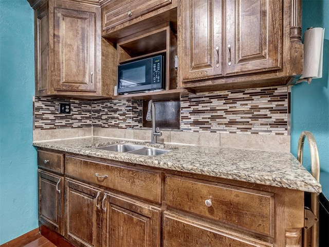 kitchen with light stone countertops, sink, and backsplash