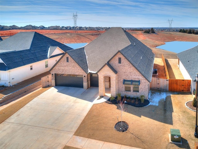 view of front of house featuring a gate, fence, a shingled roof, a garage, and brick siding